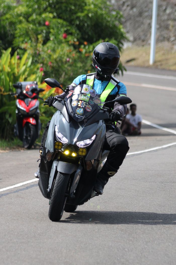 Motorcyclist wearing safety gear navigating a curve on a sunny road.
