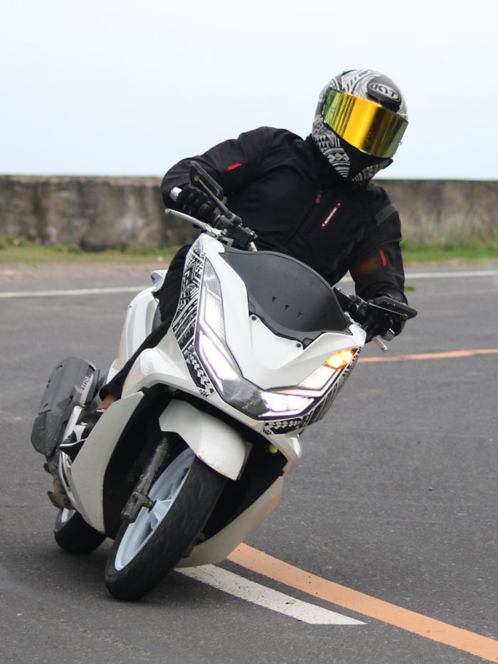 A motorcyclist expertly leans into a sharp curve on a highway, showcasing skill and precision.